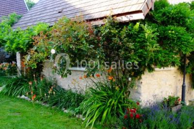 Chambre lumineuse avec deux lits simples, sol en carrelage, plafond en bois, et vue sur un jardin depuis une porte ouverte.