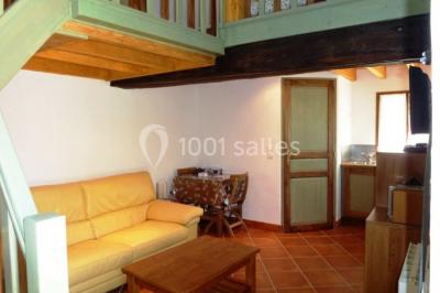 Chambre lumineuse avec deux lits simples, sol en carrelage, plafond en bois, et vue sur un jardin depuis une porte ouverte.