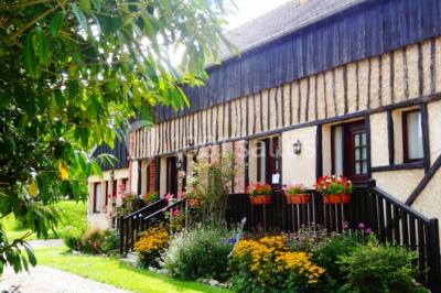 Chambre lumineuse avec deux lits simples, sol en carrelage, plafond en bois, et vue sur un jardin depuis une porte ouverte.