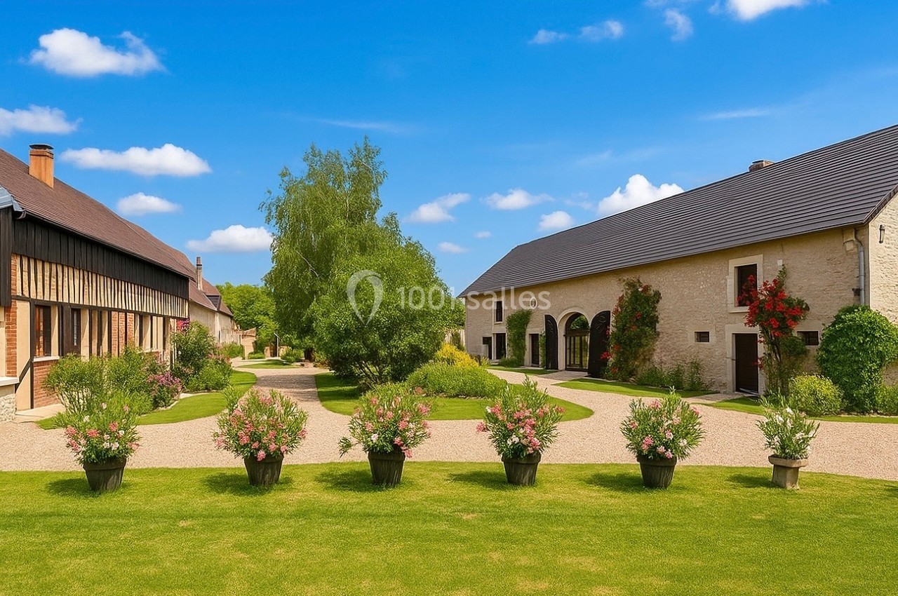 Location salle Beaulieu-sur-Loire (Loiret) - Domaine des Medards #1 Cour intérieure avec pelouse, pots de fleurs alignés, bâtiments en pierre et bois, et arbres sous un ciel bleu.