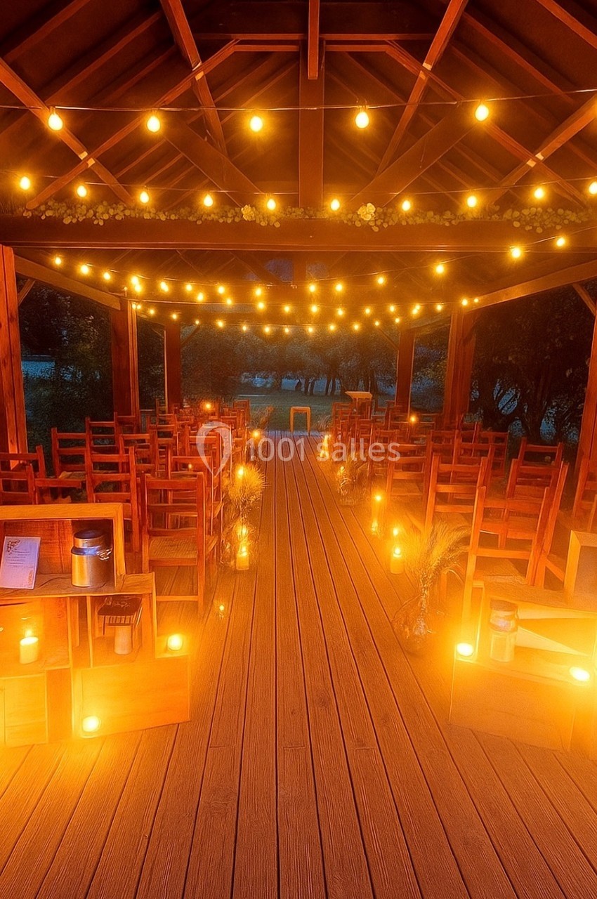Location salle Beaulieu-sur-Loire (Loiret) - Domaine des Medards #5 Salle en bois décorée pour un événement, avec des rangées de chaises, des guirlandes lumineuses et des bougies au sol.