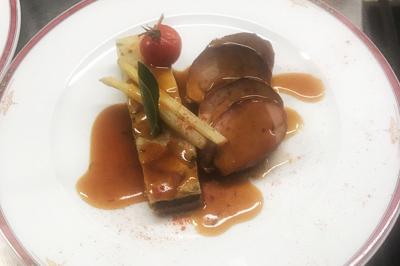 Tranche de foie gras en millefeuille avec décoration de fruits, sauce rouge et bâtonnets en chocolat.