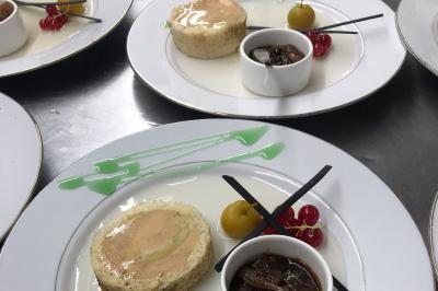 Tranche de foie gras en millefeuille avec décoration de fruits, sauce rouge et bâtonnets en chocolat.