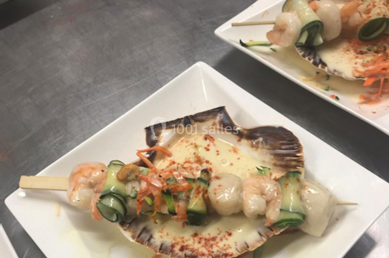 Brochette de fruits de mer avec crevettes, courgettes et sauce, servie dans une coquille Saint-Jacques sur une assiette…