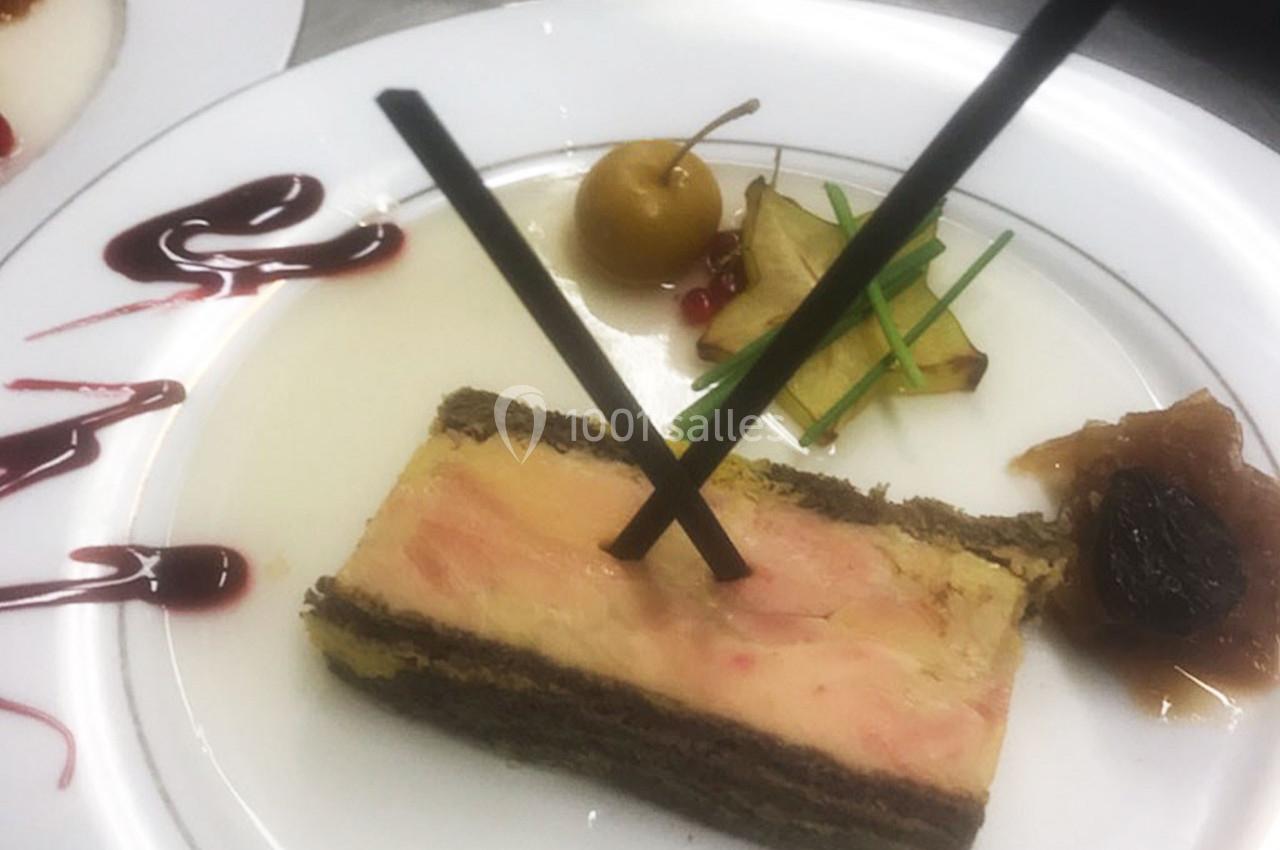 Tranche de foie gras en millefeuille avec décoration de fruits, sauce rouge et bâtonnets en chocolat.