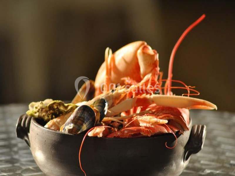 Assortiment de fruits de mer comprenant crevettes, crabe, huîtres et coquillages dans un plat en céramique sombre.