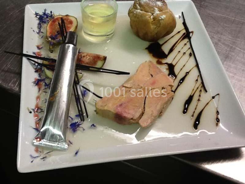 Assiette gastronomique avec foie gras, figue, réduction balsamique, pain et verrine de sauce sur une présentation soignée.