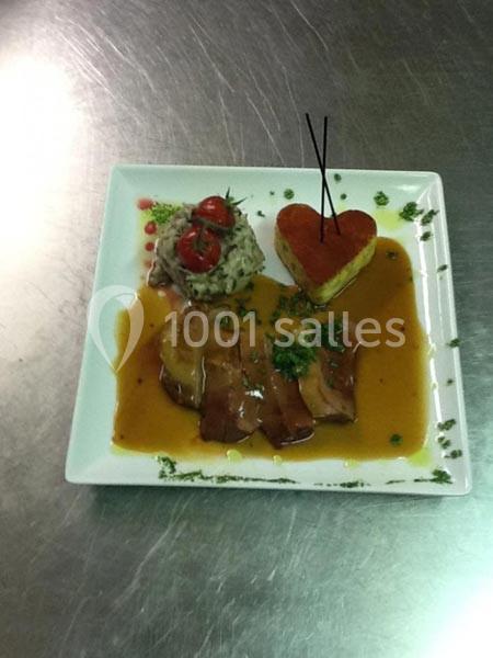 Assiette gastronomique avec viande en sauce, purée décorée de tomates cerises et accompagnement en forme de cœur.