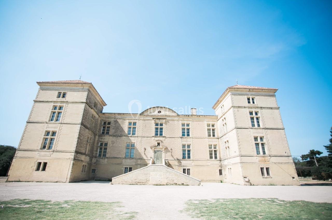 Façade d'un château en pierre avec deux tours symétriques sous un ciel bleu dégagé.