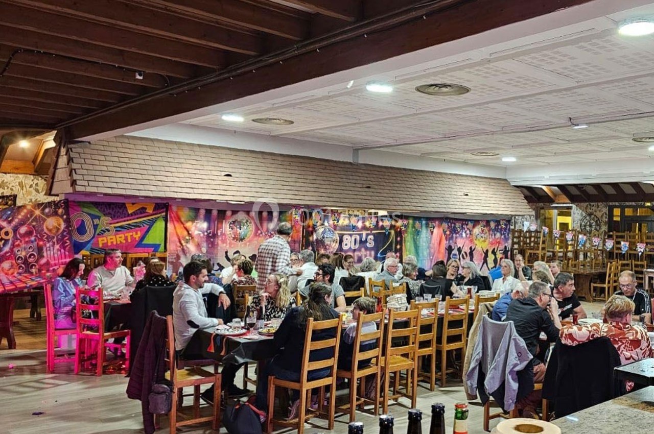 Salle décorée sur le thème des années 80 avec des invités assis à des tables lors d'un repas festif.