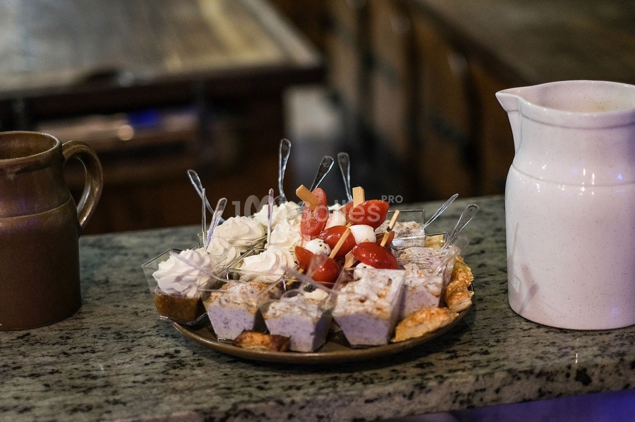 Assortiment de verrines et bouchées salées et sucrées sur un plateau, posé sur un comptoir en pierre.