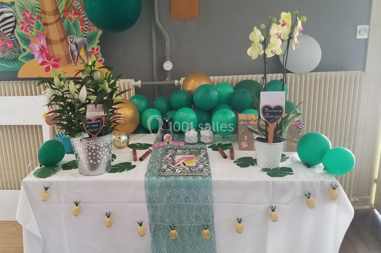 Table décorée avec des ballons verts, des plantes en pot, des orchidées et des accessoires sur le thème tropical.