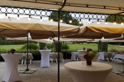 Étang calme reflétant des arbres et une pelouse verdoyante avec un bunker de golf en arrière-plan.