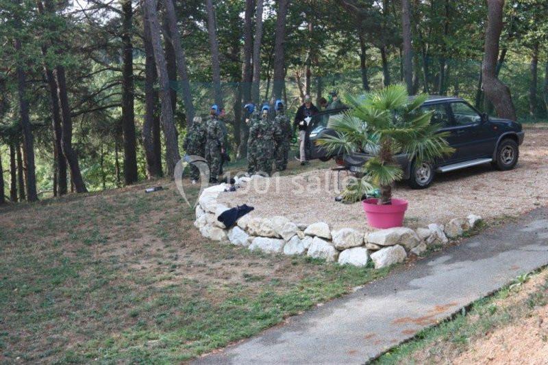 Des personnes en tenue de camouflage discutent près d'un véhicule stationné dans une clairière entourée d'arbres.