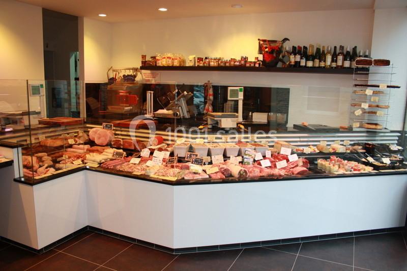 Vitrine d'une charcuterie avec un large choix de produits, dont viandes, fromages et spécialités locales.