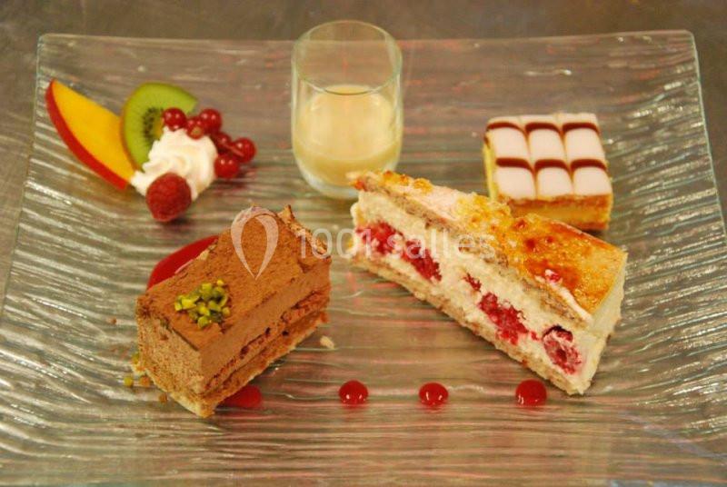 Assortiment de desserts sur une assiette en verre, incluant gâteaux, fruits frais et un verre de crème.