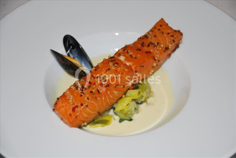 Saumon grillé avec graines de moutarde, servi sur fondue de poireaux et accompagné de moules dans une sauce crémeuse.