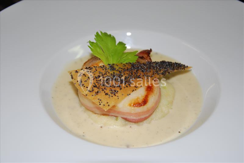 Plat gastronomique composé de poisson enroulé de lard, purée, sauce crémeuse, feuille croustillante et graines de pavot.