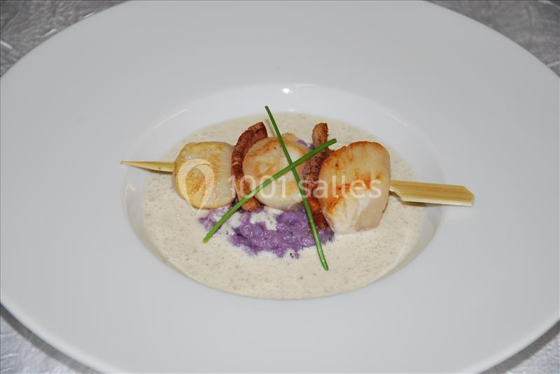 Brochette de noix de Saint-Jacques sur purée violette, nappée d'une sauce crémeuse et décorée de brins de ciboulette.