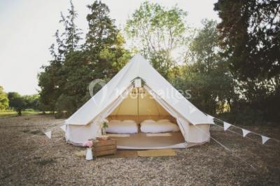 Miniature Location salle Montagnac (Hérault) - Domaine de la Grangette #30 Tente en toile beige installée sur un sol gravillonné, entourée d'arbres, avec des lits aménagés à l'intérieur.