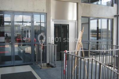 Miniature Location salle Rouen (Seine-Maritime) - Vue Sur Seine #3 Espace intérieur lumineux avec fauteuils rouges et noirs, tables hautes, plantes et stands d'exposition en arrière-plan.