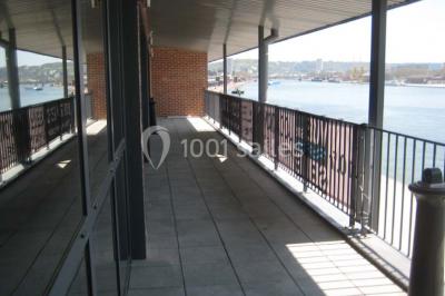 Miniature Location salle Rouen (Seine-Maritime) - Vue Sur Seine #4 Espace intérieur lumineux avec fauteuils rouges et noirs, tables hautes, plantes et stands d'exposition en arrière-plan.