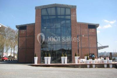 Miniature Location salle Rouen (Seine-Maritime) - Vue Sur Seine #6 Espace intérieur lumineux avec fauteuils rouges et noirs, tables hautes, plantes et stands d'exposition en arrière-plan.