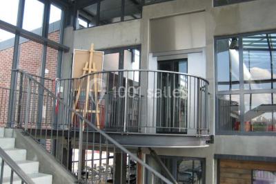 Miniature Location salle Rouen (Seine-Maritime) - Vue Sur Seine #7 Espace intérieur lumineux avec fauteuils rouges et noirs, tables hautes, plantes et stands d'exposition en arrière-plan.