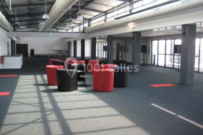 Miniature Location salle Rouen (Seine-Maritime) - Vue Sur Seine #8 Espace intérieur lumineux avec fauteuils rouges et noirs, tables hautes, plantes et stands d'exposition en arrière-plan.