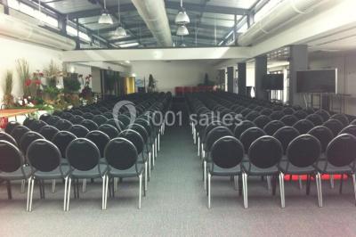 Miniature Location salle Rouen (Seine-Maritime) - Vue Sur Seine #17 Espace intérieur lumineux avec fauteuils rouges et noirs, tables hautes, plantes et stands d'exposition en arrière-plan.