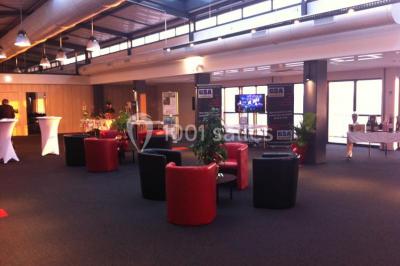 Miniature Location salle Rouen (Seine-Maritime) - Vue Sur Seine #20 Espace intérieur lumineux avec fauteuils rouges et noirs, tables hautes, plantes et stands d'exposition en arrière-plan.