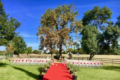 Miniature Location salle Le Crès (Hérault) - Domaine du Mas du Pont #6 Un couple en tenue de mariage pose devant un groupe de cavaliers alignés sur des chevaux dans un espace verdoyant.