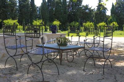 Miniature Location salle Avignon (Vaucluse) - Domaine de Rochegude #13 Façade d'une maison provençale avec terrasse ombragée, tables en fer forgé et grand arbre au premier plan.