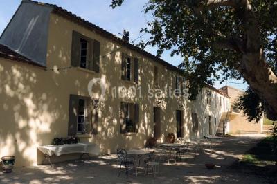 Miniature Location salle Avignon (Vaucluse) - Domaine de Rochegude #26 Façade d'une maison provençale avec terrasse ombragée, tables en fer forgé et grand arbre au premier plan.