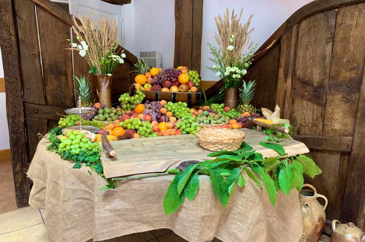 Table décorée avec des fruits variés, des grappes de raisin, des oranges et des éléments végétaux sur une nappe en toile de…
