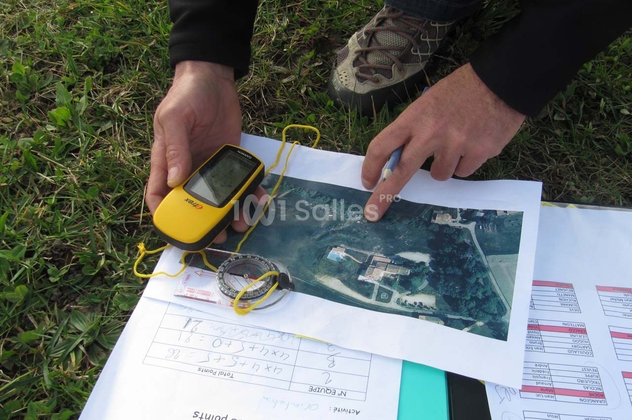 Une personne utilise un GPS portable et une carte aérienne pour analyser une zone sur le terrain.