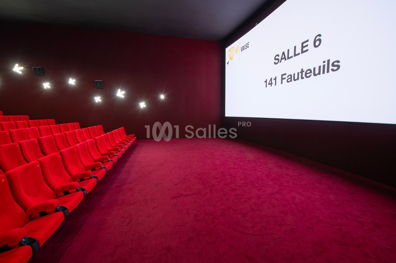 Salle de cinéma avec des fauteuils rouges, un écran affichant ’Salle 6, 141 fauteuils’ et un sol recouvert de moquette rouge.