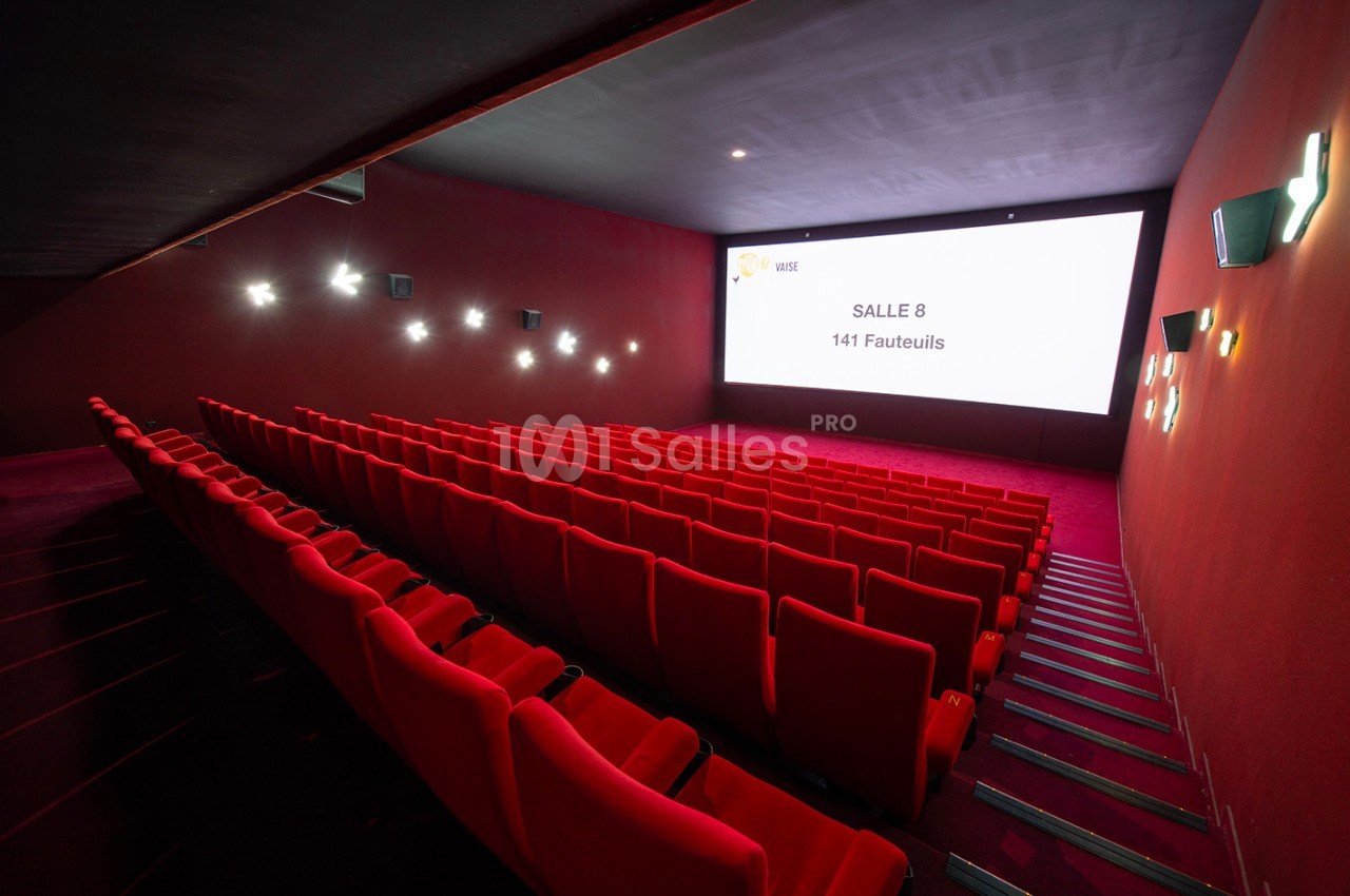 Salle de cinéma vide avec des rangées de fauteuils rouges et un écran affichant ’Salle 8 - 141 Fauteuils’.