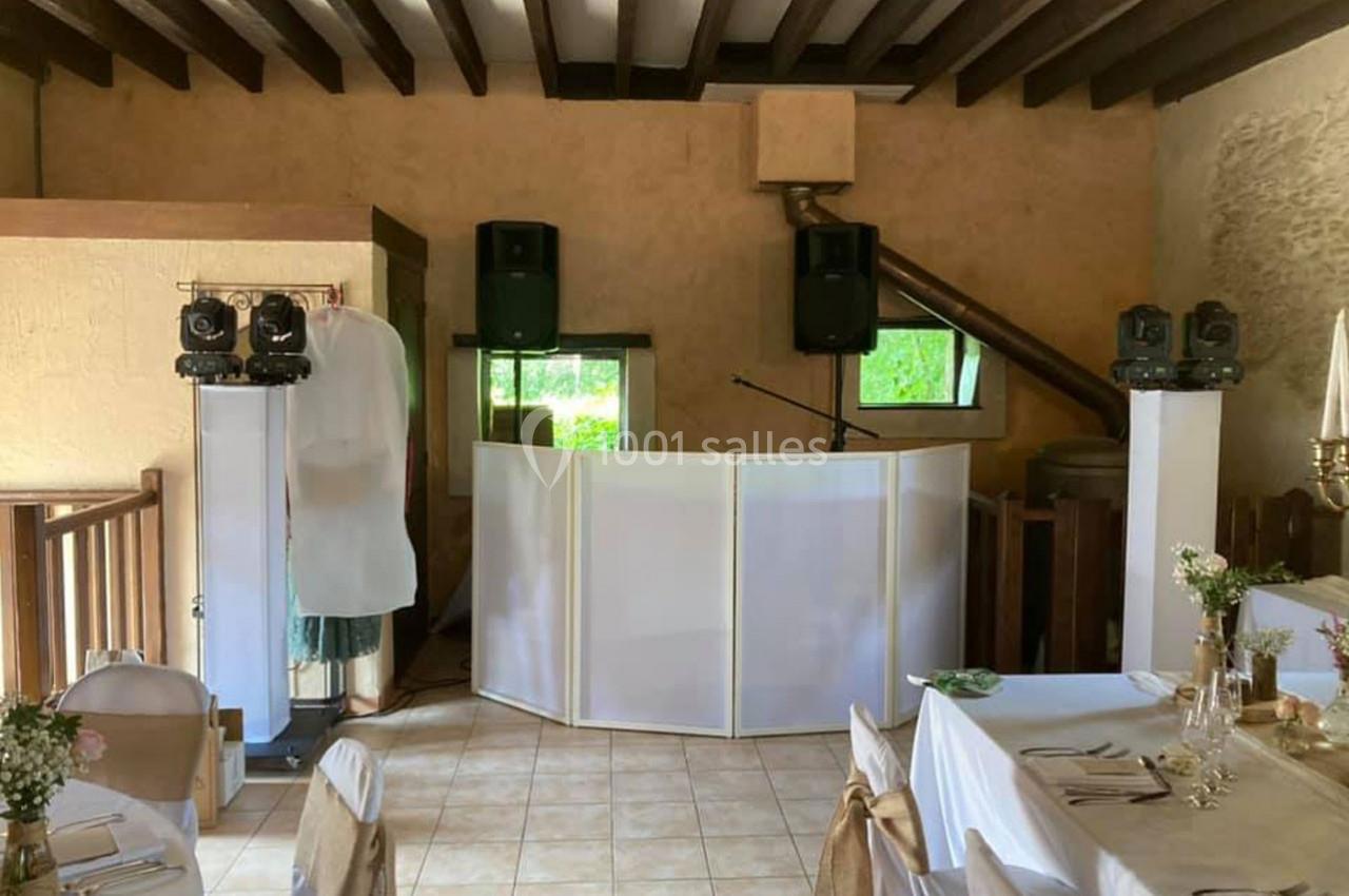 Installation d'un espace DJ avec enceintes et éclairages dans une salle de réception décorée pour un événement.