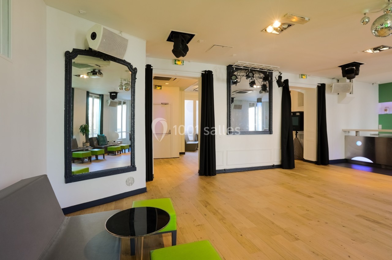 Salle lumineuse avec parquet clair, miroirs muraux, rideaux noirs, mobilier moderne et éclairages suspendus.