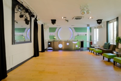 Salon lumineux avec parquet en bois clair, cheminée, fauteuils bleus et moulures au plafond.