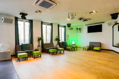 Salon lumineux avec parquet en bois clair, cheminée, fauteuils bleus et moulures au plafond.