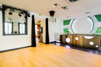 Salon lumineux avec parquet en bois clair, cheminée, fauteuils bleus et moulures au plafond.