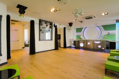 Salon lumineux avec parquet en bois clair, cheminée, fauteuils bleus et moulures au plafond.