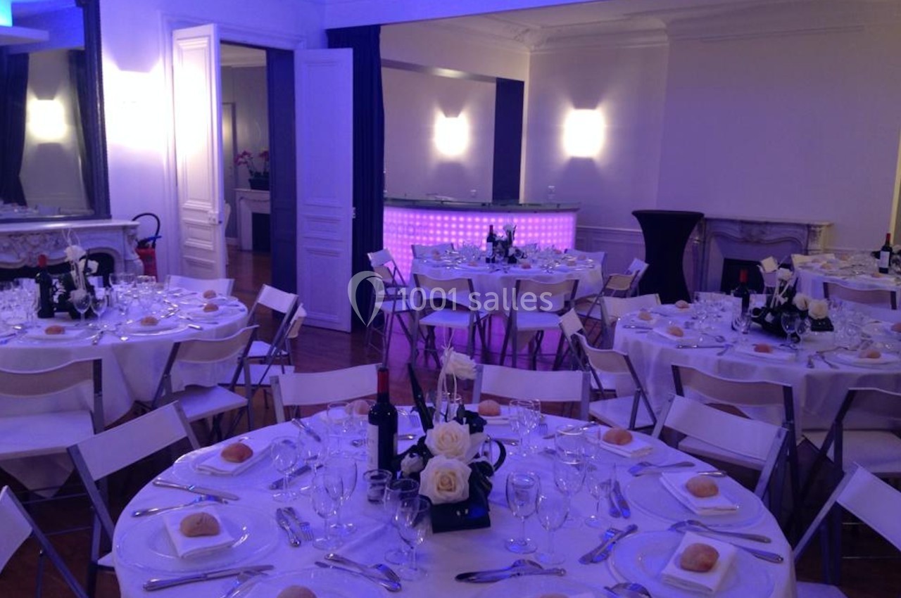 L'Appart Lafayette - diner assis de 60 invités en tables rondes Salle de réception élégante avec tables rondes dressées, nappes blanches, couverts et éclairage tamisé violet.