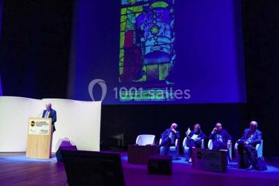 Un groupe de musiciens joue sur scène pendant qu'un public danse dans une salle éclairée et animée.