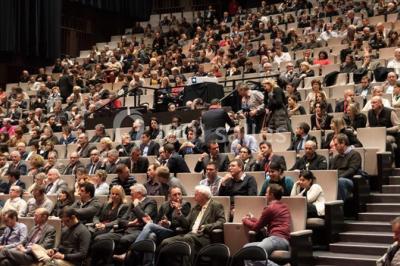 Un groupe de musiciens joue sur scène pendant qu'un public danse dans une salle éclairée et animée.