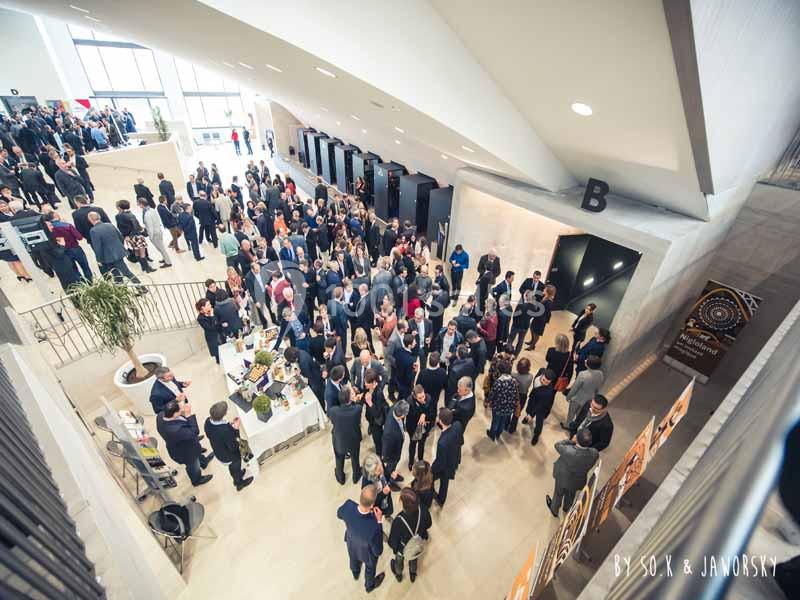 Vue aérienne d'un hall animé avec de nombreuses personnes en tenue professionnelle lors d'un événement ou d'une réception.