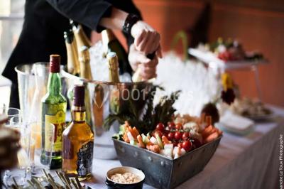 Jardin avec pelouse, tables et chaises rouges, scène en bois, entouré d'arbres et d'une maison à colombages.