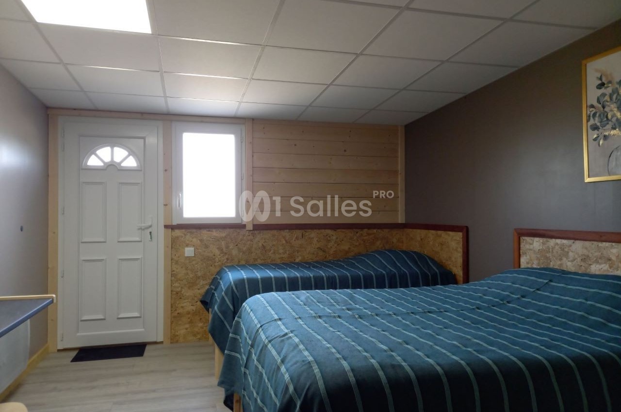 Deux lits simples avec couvre-lits rayés dans une chambre lumineuse avec porte et fenêtre.